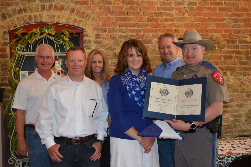 Image of six people one of which is a police officer holding an award.
