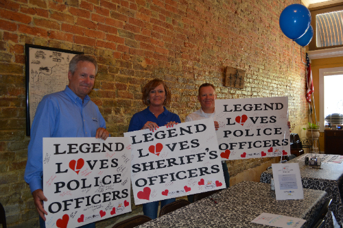 Image of two men and a women holding up signs that say, "Legend Loves Police Officers".