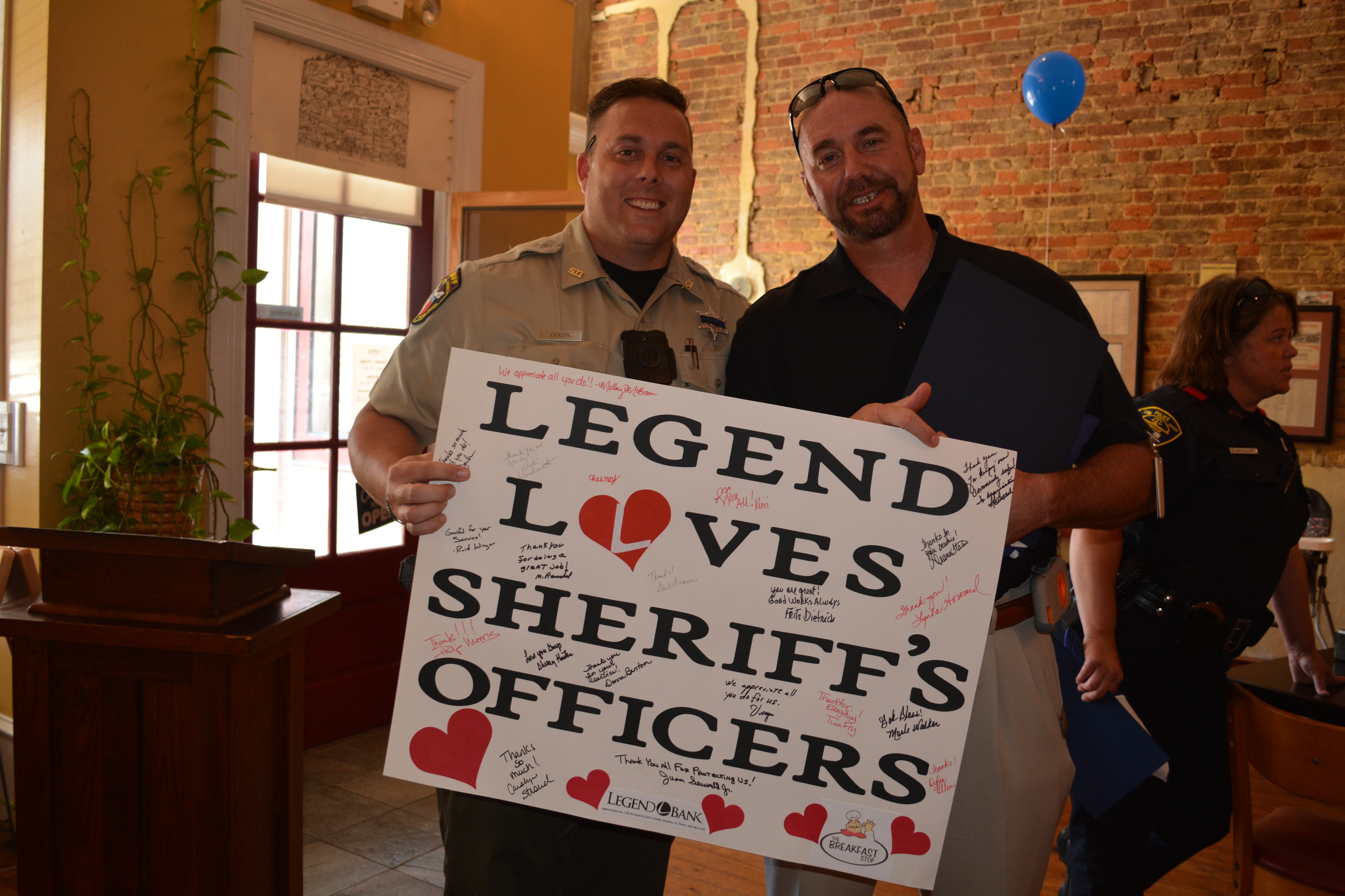 Image of two men holding up a sign saying, "Legend Loves Sheriff's Officers".