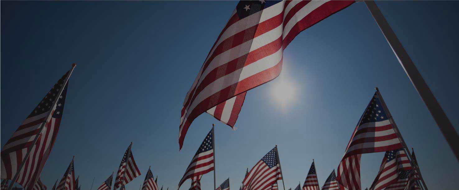 Image of several American Flags with the Sun in the background.